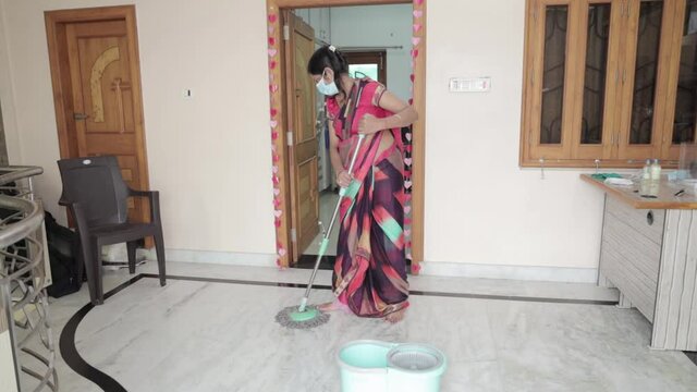 Indian woman wearing mask cleaning floor with mop sanitizing . Mopping Floor At Home, protection against covid-19 /  coronavirus, House Hygiene and Cleaning Service Concept. full hd 