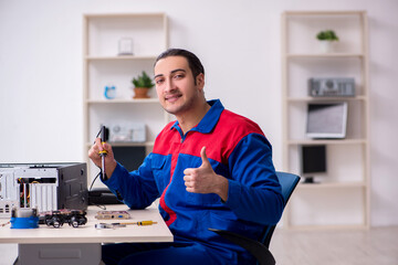 Naklejka na ściany i meble Young male repairman repairing computer