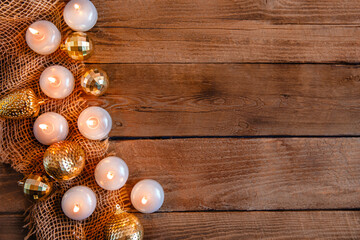 Lit candles, Christmas tree Golden baubles and burlap on a wooden background. New year's flat layout with space for text