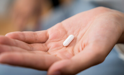 Obraz na płótnie Canvas Hand holding a white pill, Migraine painkiller.
