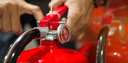 Fire protection engineer check the safety pin of red fire extinguishers tank in the building...
