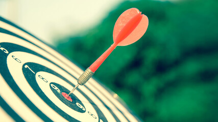 Bulls eye or dart board has red dart arrow throw hitting the center of a shooting target for...