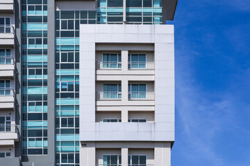 Geometric rectangle pattern of glass windows and balcony on exterior view of modern high building with blue sky background