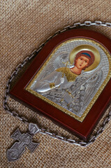 Silver pectoral cross with a chain around the Icon of the Archangel Michael on sackcloth.