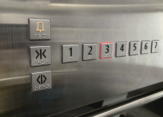 Close-up of the square floor button inside an office building elevator with floor numbers to choose from and menus. © Tiwat