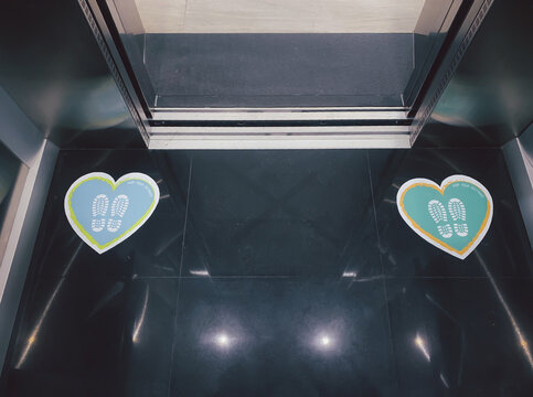 Heart-shaped Placards Printed On The Area In The Lift Inform People To Keep A Distance Of 6 Feet Apart To Prevent The Spread Of The Coronavirus, Or COVID-19.