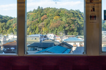 view of autumn mountain and houses seen from the train window