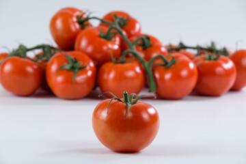 Mehrere rote Tomaten auf einem hellen Hintergrund - im Vordergrund eine einzelne saftige frische Tomate