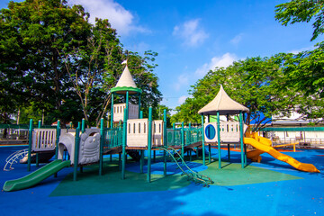 Colorful children playground activities in public park surrounded by green trees 