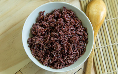Riceberry in white bowl on wood table for health food content.