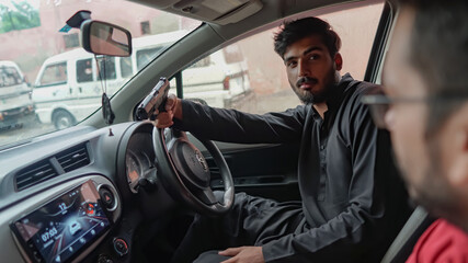 close up of a young man in a car holding a gun