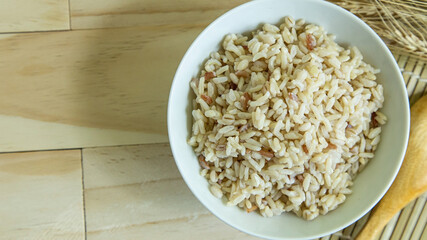  BROWN RICE in white bowl on wood table for health food content..
