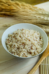  BROWN RICE in white bowl on wood table for health food content..