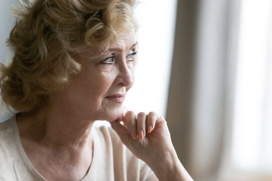 Close up thoughtful mature woman looking to aside, dreaming about future, planning, pensive middle aged female lost in thoughts, memories, thinking about opportunities, standing at home