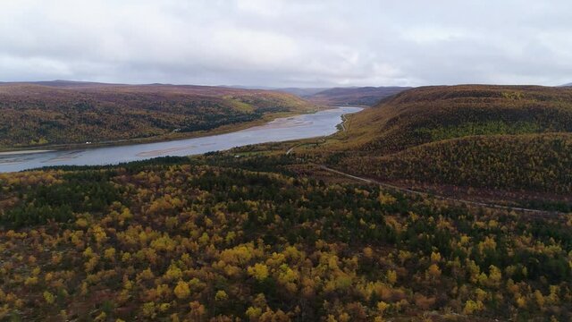 Aerial view overlooking the Tenojoki river and the scenic, finnish national road 970 ,dark rainy, autumn day, near Utsjoki, in Lapland, Finland - tracking, drone shot