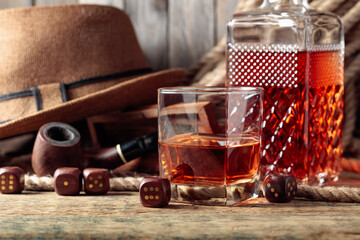Whiskey, pipe, and dice on an wooden table.