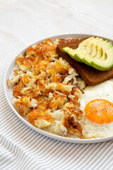 Tasty Homemade Fried Hashbrowns and Eggs on a plate, side view.
