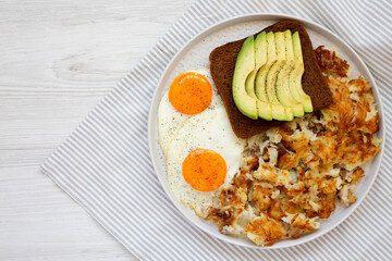 Tasty Homemade Fried Hashbrowns and Eggs on a plate on a white wooden background, top view. Flat lay, overhead, from above. Space for text.