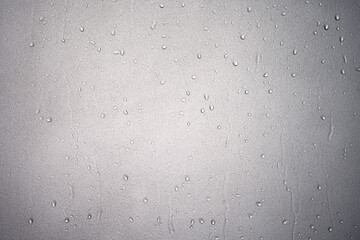 Water droplet on frosted glass or wet translucent window from rain on rainy season or water drop and splashes in bathroom wall or shower room with white light for texture background