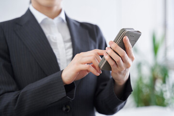 オフィスでスマホを操作する日本人女性ビジネスウーマン
