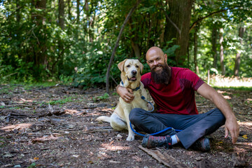 Active young bearded man with his dog on hike in high mountains