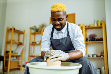 mixed race man making a vase in pottery studio
