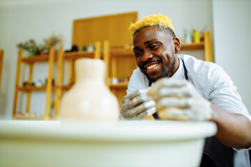 Portrait of positive latin hispanic brazilian man making ceramic pot on pottery wheel