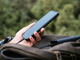 The black smartphone is connected to the power Bank. Portable chargers and external batteries in...