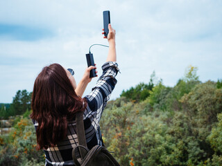 A girl in a plaid shirt and glasses tries to catch a cell phone or Internet connection or takes a...