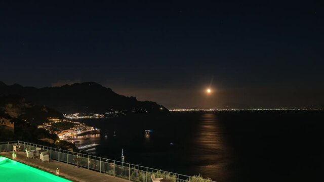 Amalfi, Italy. September 4ht, 2020. Timelaspe video of rising moon and stras from the Amalfi Coast with swimming pool in foreground and Amalfi lights on the left.