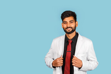 Handsome modern indian / asian doctor with stethoscope, tie and white coat on blue background