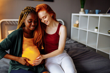 cheerful afro and european lesbian women at home on the bed