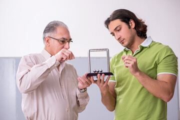 Old professor physicist and young student in the classroom