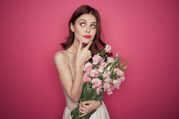 Obraz na płótnie Canvas beautiful woman with a bouquet of flowers on a pink background in a light dress makeup model