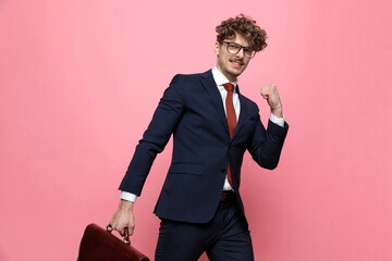 confident young man holding suitcase and celebrating victory
