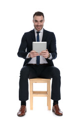 Happy businessman smiling and holding tablet while sitting