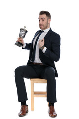 Proud businessman holding trophy and pointing to himself