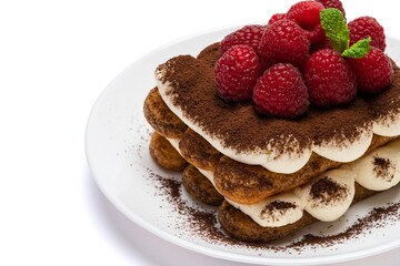 portion of Classic tiramisu dessert with raspberries on ceramic plate isolated on white background - clipping path