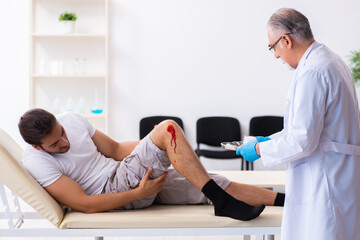 Fototapeta premium Leg injured man visiting old doctor in first aid concept