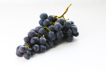 Black grapes, large fresh fruits with green leaves on a white background