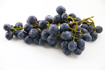 Black grapes, large fresh fruits with green leaves on a white background