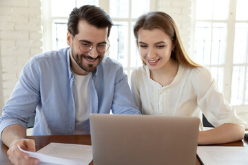 Smiling man and woman using laptop, looking at screen, colleagues or students working on project together, teamwork concept, young couple checking documents, finances, reading good news