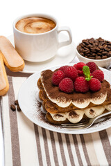portion of Classic tiramisu dessert with raspberries and cup of fresh hot espresso isolated on white background - clipping path