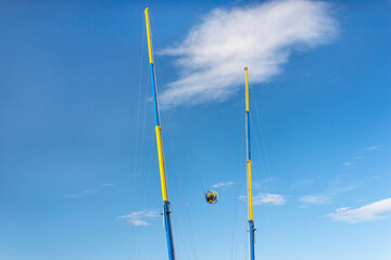 Launching a catapult in an amusement park with two people sitting in a round ball against a blue...