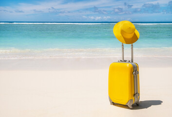 Yellow suitcase with yallow hat on empty tropical beach with turquoise water on background, summer...