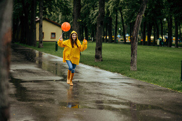 Happy woman runs with balloon in rainy day