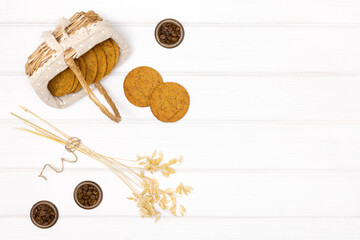 Fototapeta na wymiar Oatmeal cookies with oat stems ears and coffee beans on white wood table. Top view. Copy space. Rustic food background