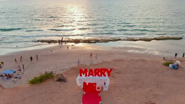 "Marry me" proposal sign on a picturesque beach at a sunset, 4k aerial drone view