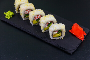 Uramaki sushi rolls with surimi on a black slate