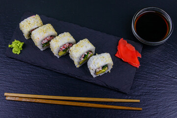 Uramaki sushi rolls with surimi on a black slate